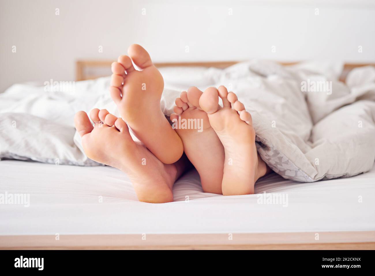 Nous allons simplement rester au lit aujourd'hui. Photo d'un couple pieds en poking hors de sous une couette. Banque D'Images