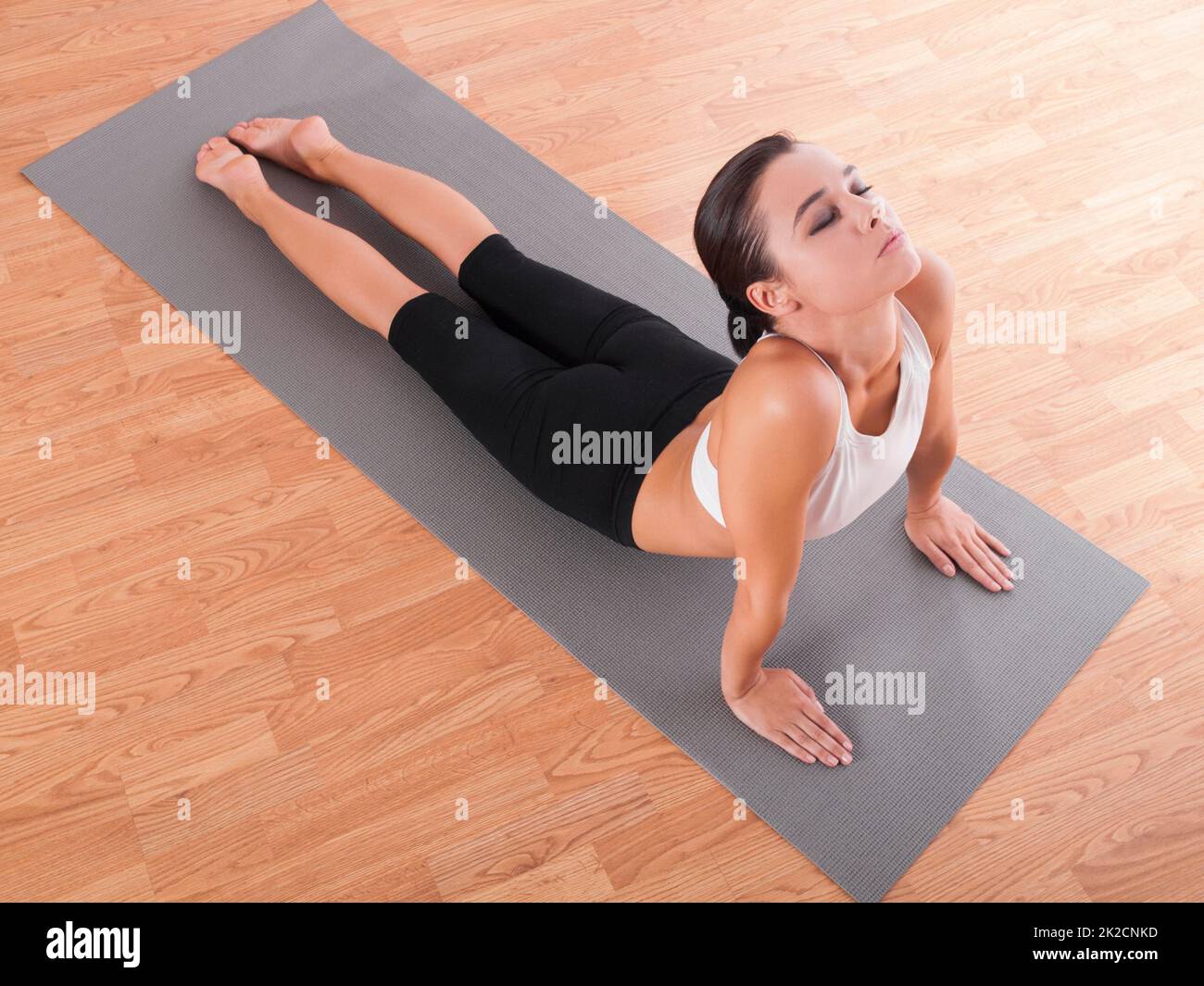 Posture Cobra. Photo d'une belle jeune femme faisant du yoga sur un tapis d'exercice. Banque D'Images