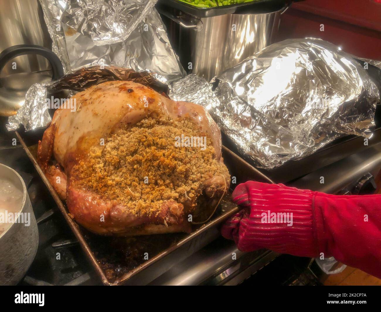 dinde farcie dans un plat à rôtir avec feuille d'aluminium et gant chaud rouge Banque D'Images