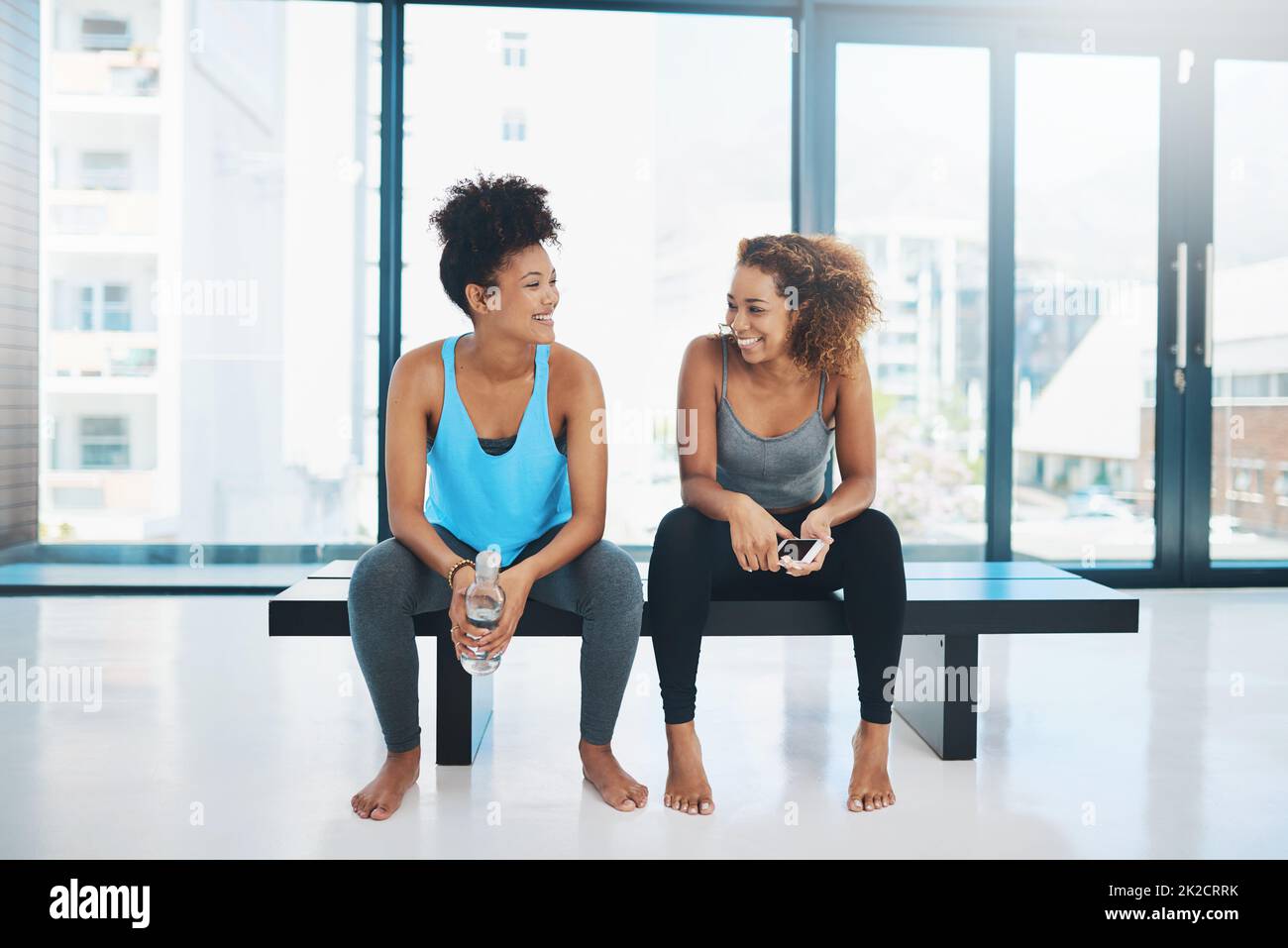 Prenons un peu de reniflard. Portrait de deux jeunes femmes en forme assis sur un banc et ayant une discussion avant une session de yoga dans un studio. Banque D'Images