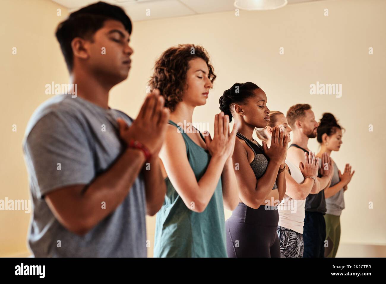 Le yoga est une œuvre de cœur. Prise de vue d'un groupe de jeunes hommes et femmes méditant dans un cours de yoga. Banque D'Images