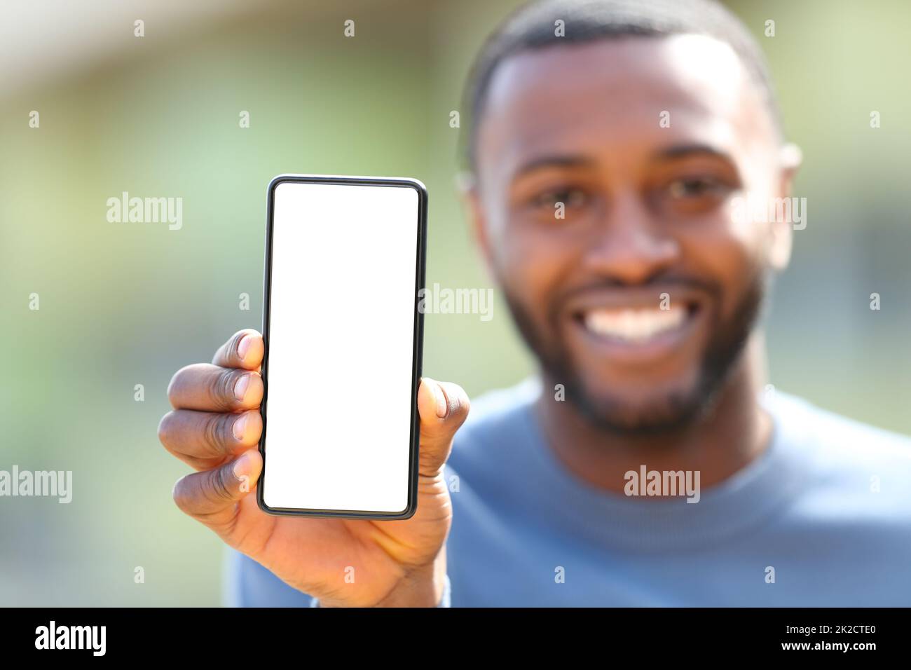 Homme heureux avec une peau noire montrant un écran de téléphone vide Banque D'Images