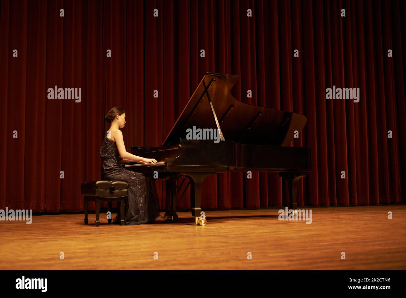 Partager son cadeau avec la foule. Prise de vue d'une jeune femme jouant du piano lors d'un concert musical. Banque D'Images
