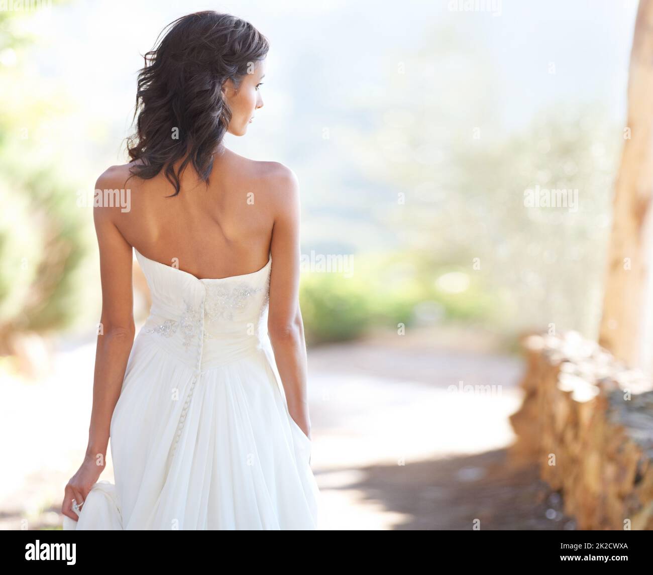 Marche fièrement vers l'avenir. Une jeune mariée regardant sur le côté tout en marchant sur un chemin à l'extérieur. Banque D'Images