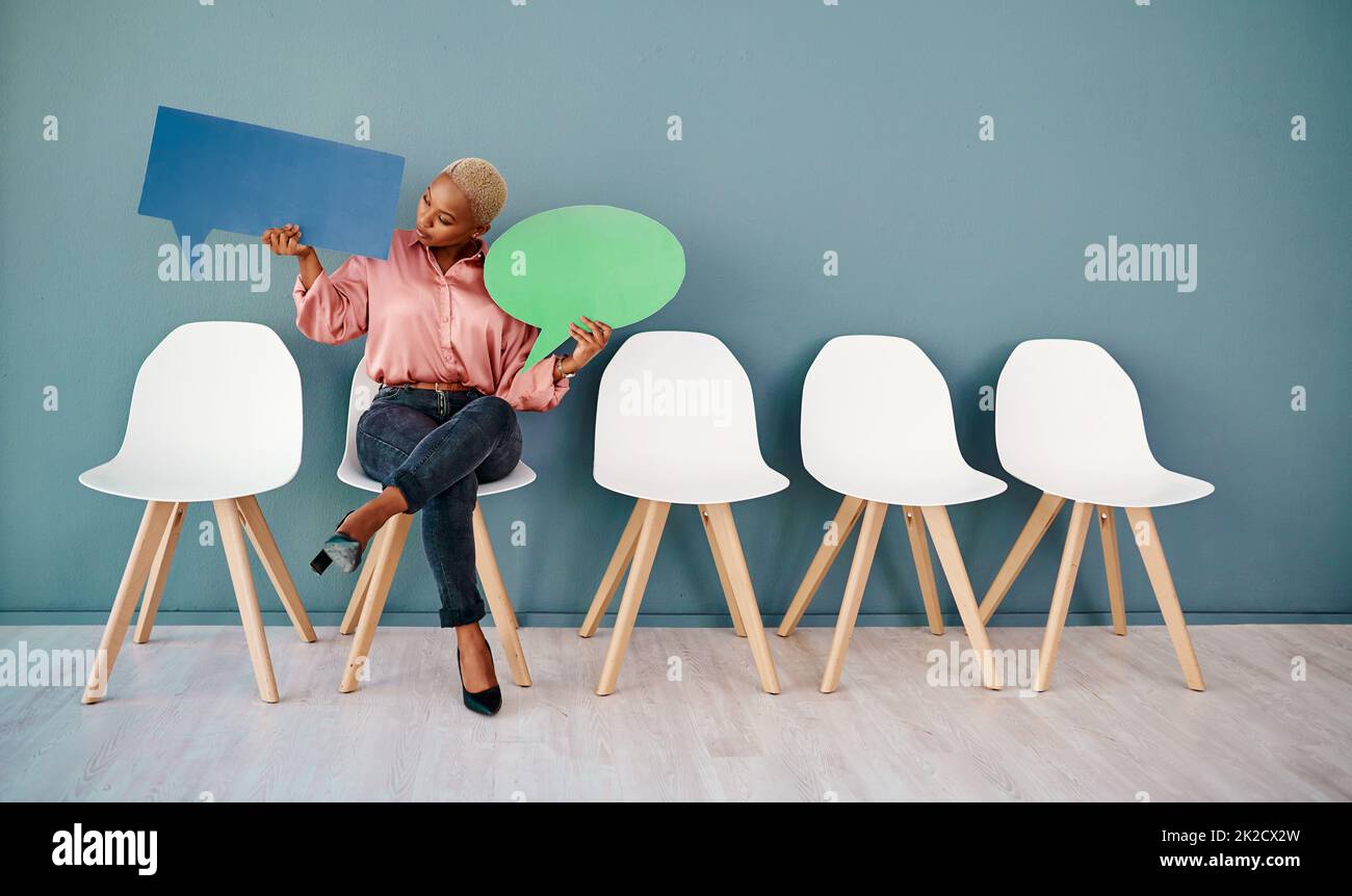 Que dites-vous cher ? Photo en studio d'une jeune femme d'affaires attirante tenant des bulles de la parole tout en restant dans la ligne sur un fond gris. Banque D'Images