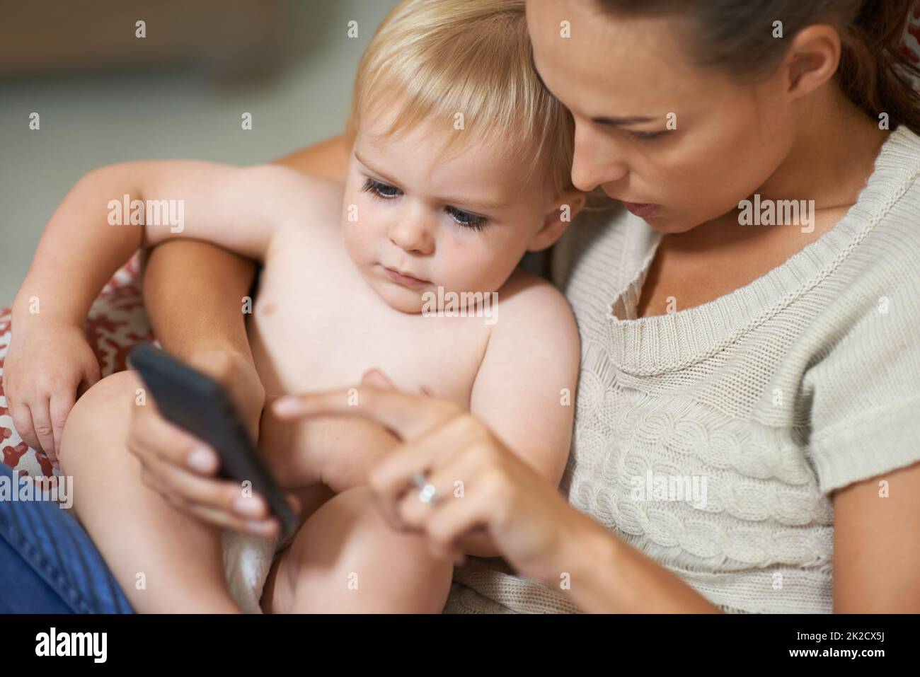 Regardez ça Une mère montrant quelque chose à son bébé garçon sur son téléphone portable. Banque D'Images
