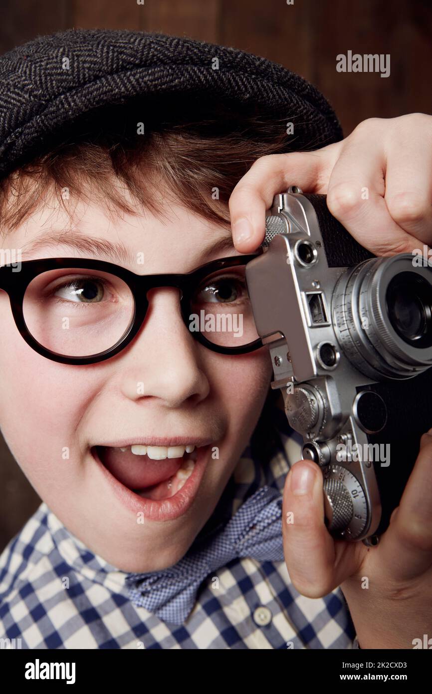 Quel cliché parfait. Jeune garçon en vêtements rétro portant des lunettes et tenant son appareil photo. Banque D'Images