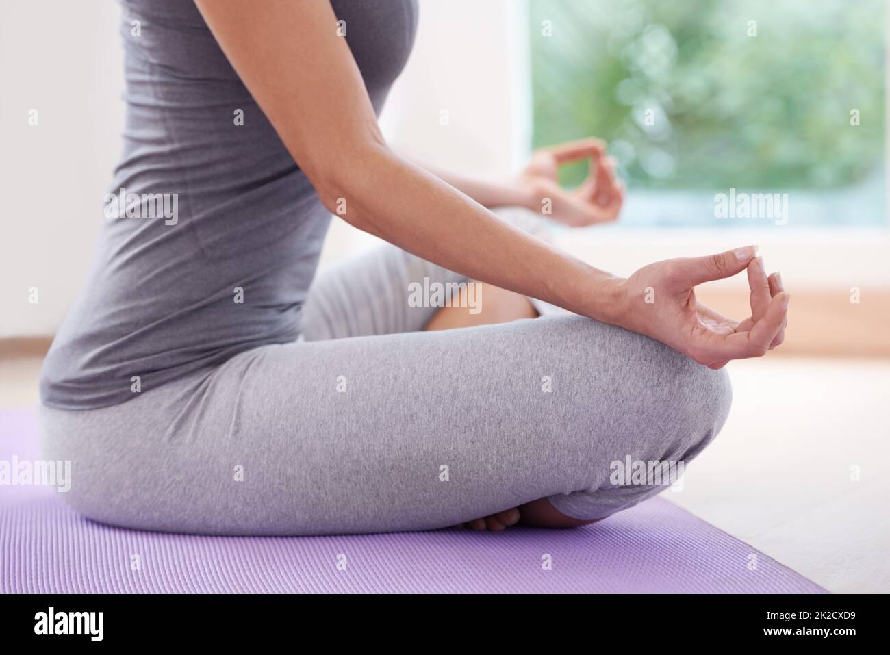 Sérénité par le yoga. Image rognée d'une femme assise à pattes croisées et méditant. Banque D'Images