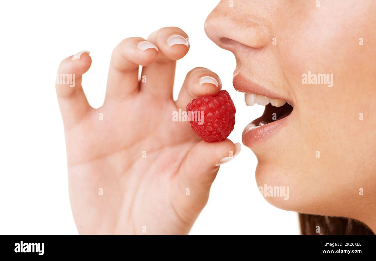 Savourez une délicieuse framboise. Profil court d'une femme sur le point de manger une framboise. Banque D'Images