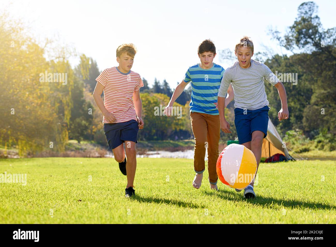 Souvenirs d'été en mouvement. Photo d'un groupe d'adolescents jouant avec un ballon à l'extérieur. Banque D'Images