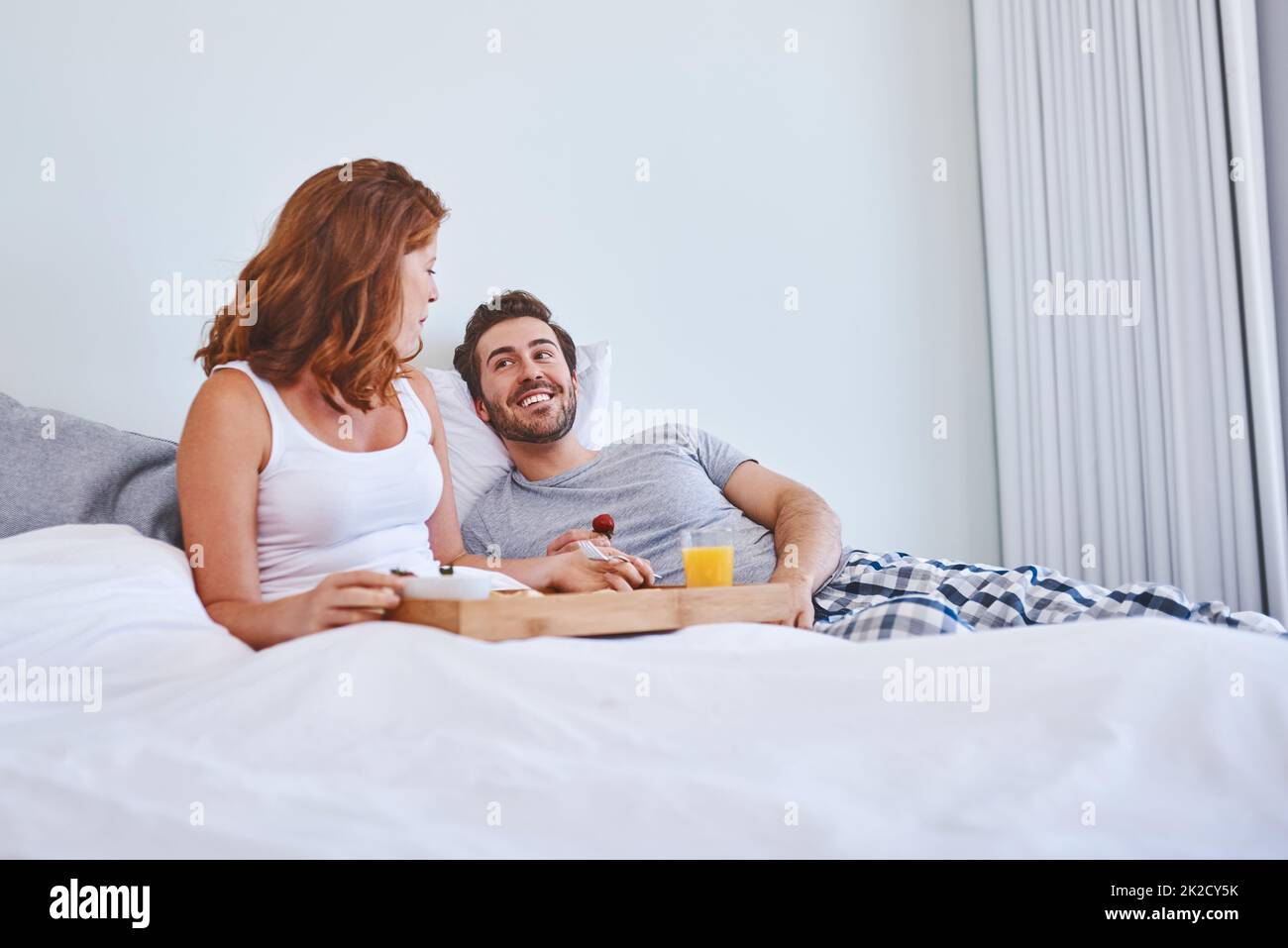 Commencez la journée avec de la nourriture et de l'amour. Photo d'un couple prenant le petit déjeuner au lit ensemble à la maison. Banque D'Images
