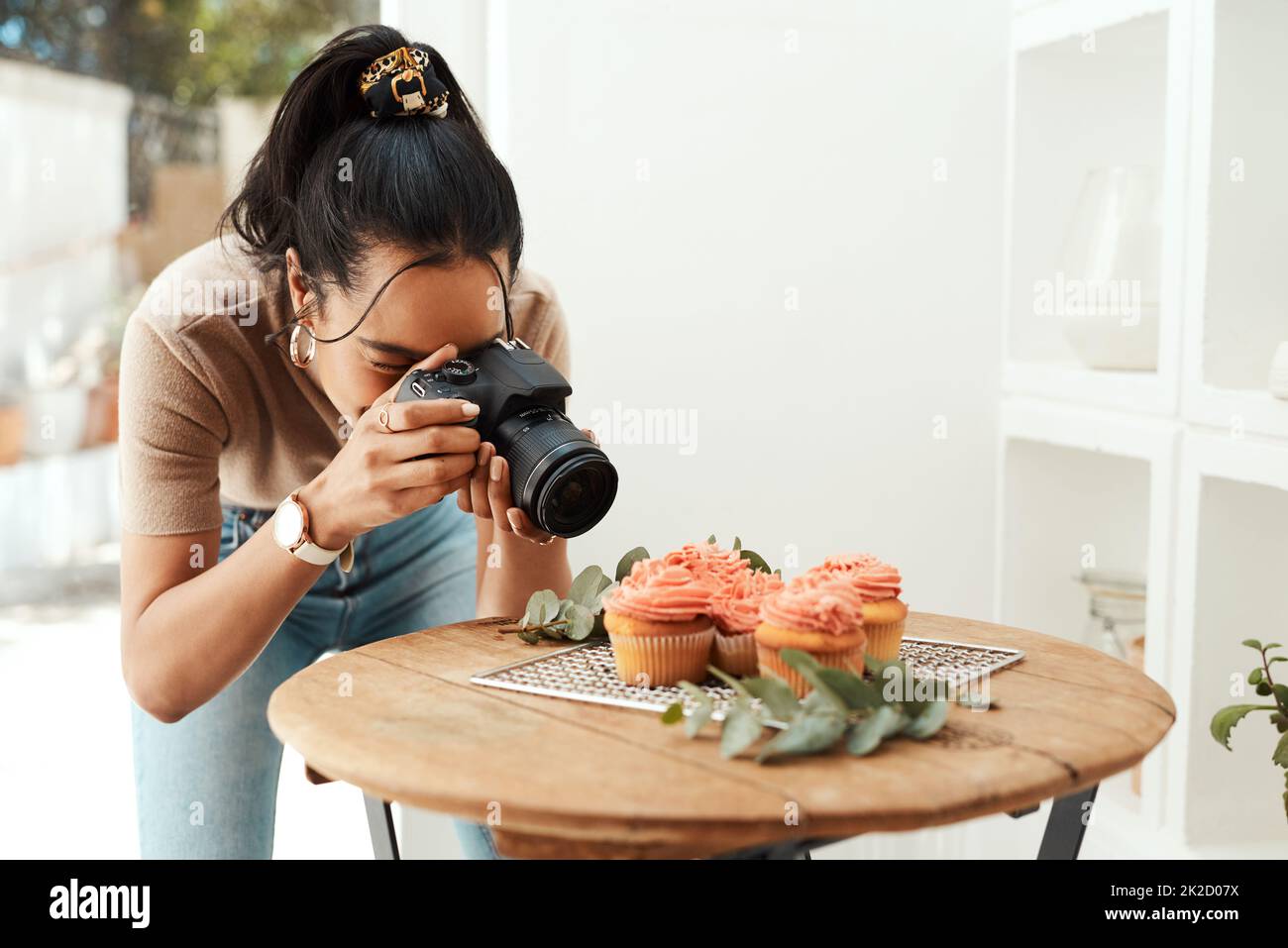Se rapprocher suffisamment pour capturer les détails. Photo rognée d'une jeune femme d'affaires attirante utilisant son appareil photo pour photographier des cupcakes pour son blog. Banque D'Images
