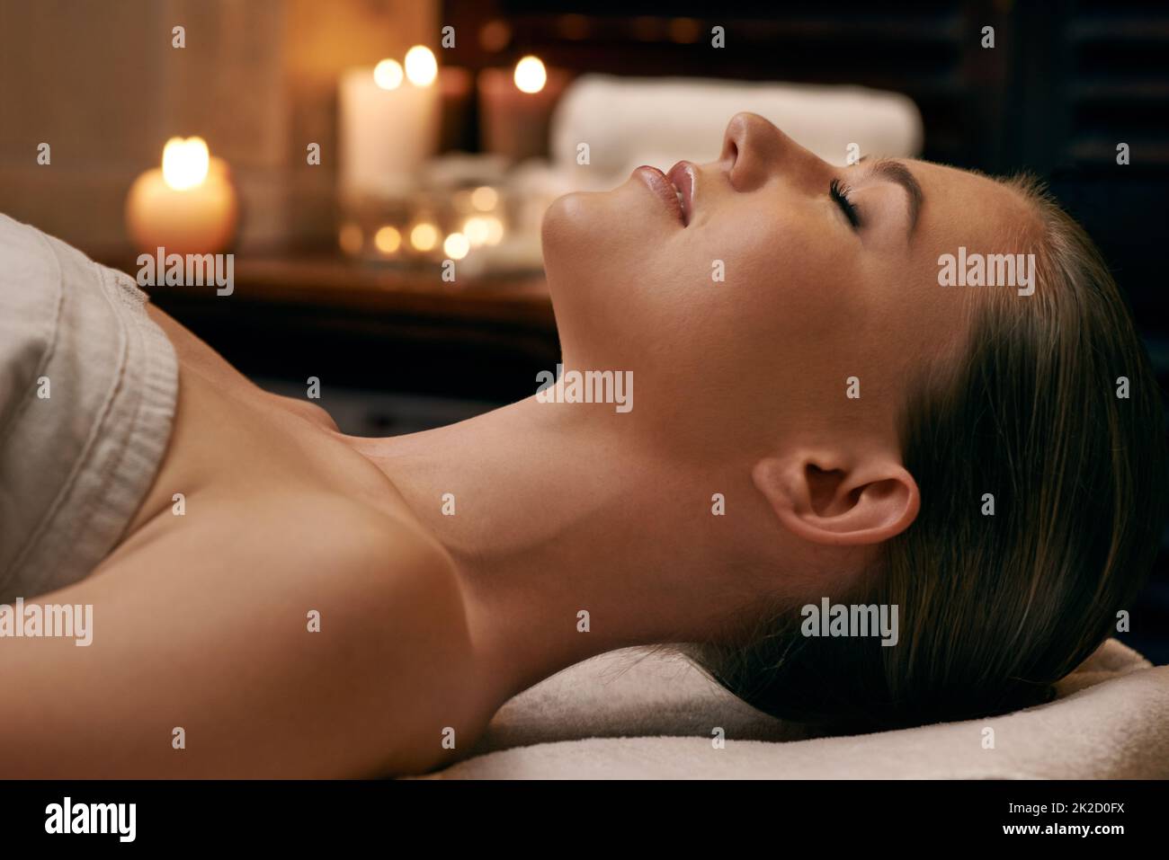 Se faire dorloter de haut en bas. Une jeune femme couché avec les yeux fermés sur un lit de massage. Banque D'Images