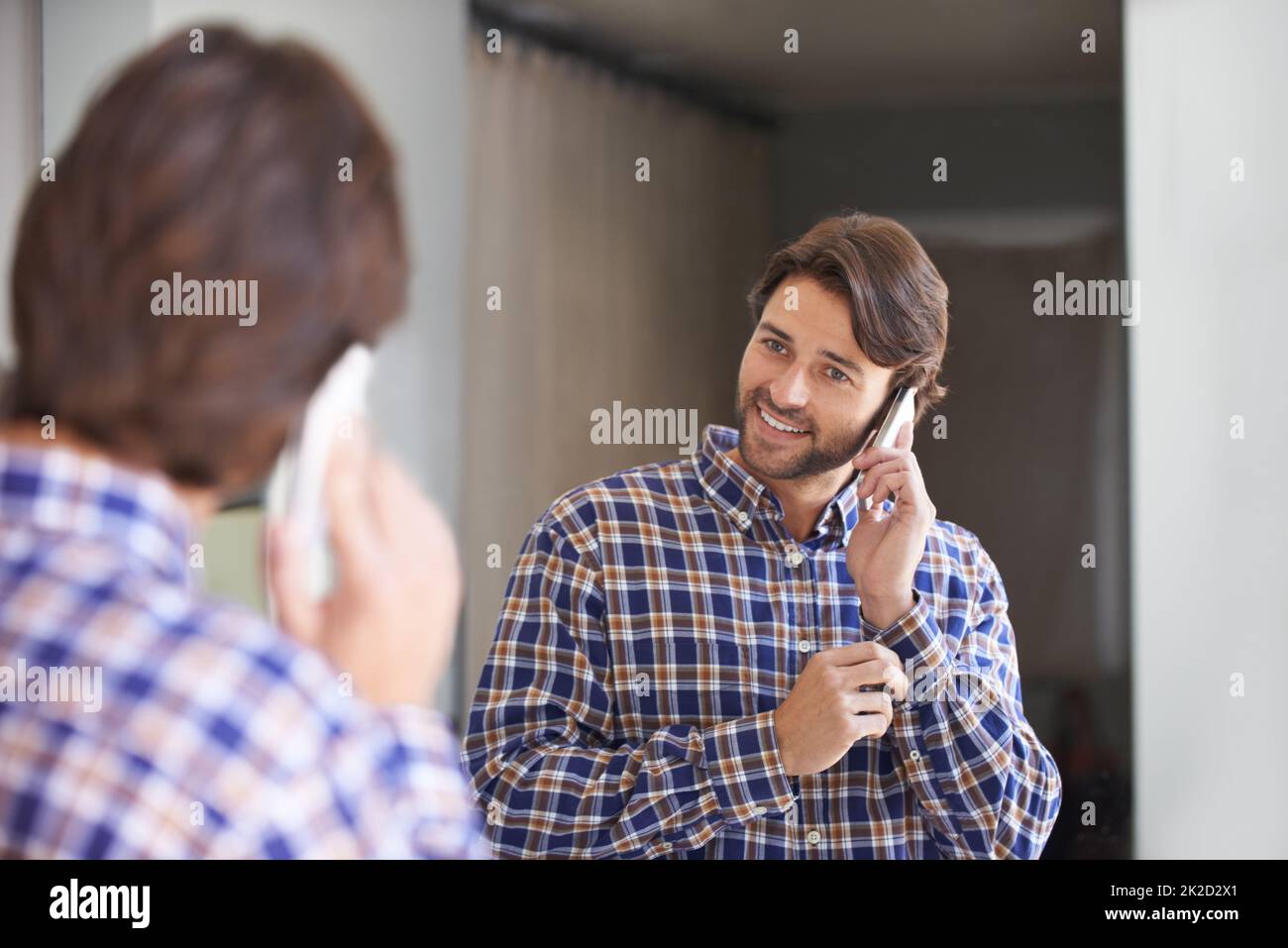 Préparer son emploi du temps avant de partir au travail. Photo d'un beau homme parlant au téléphone tout en se préparer au travail. Banque D'Images