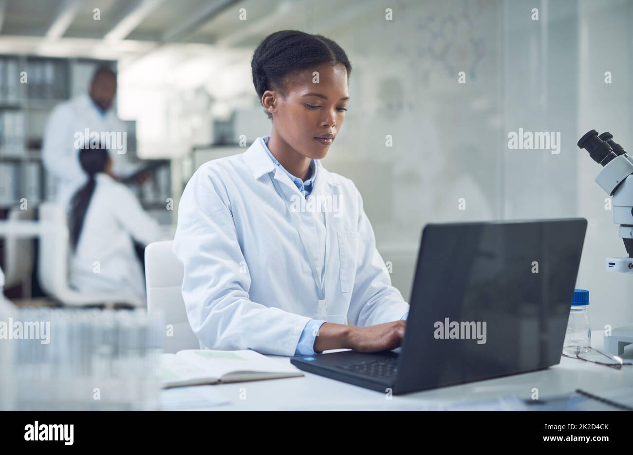 Plus elle travaille fort, plus la guérison est proche. Photo d'un jeune scientifique utilisant un ordinateur portable tout en effectuant des recherches dans un laboratoire. Banque D'Images