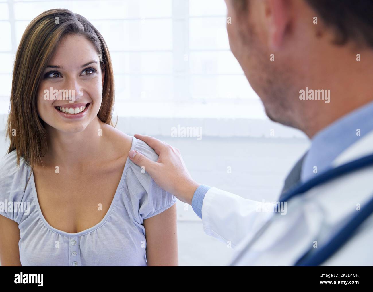 Vous êtes en forme. Une jeune femme étant rassurée par son médecin au cours d'une consultation. Banque D'Images