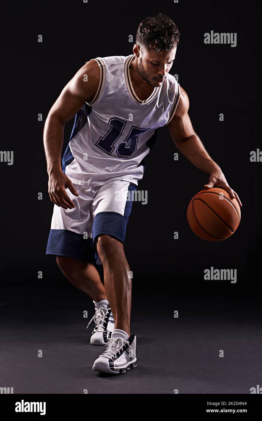 Dribbling pro. Photo studio d'un joueur de basket-ball sur fond noir. Banque D'Images