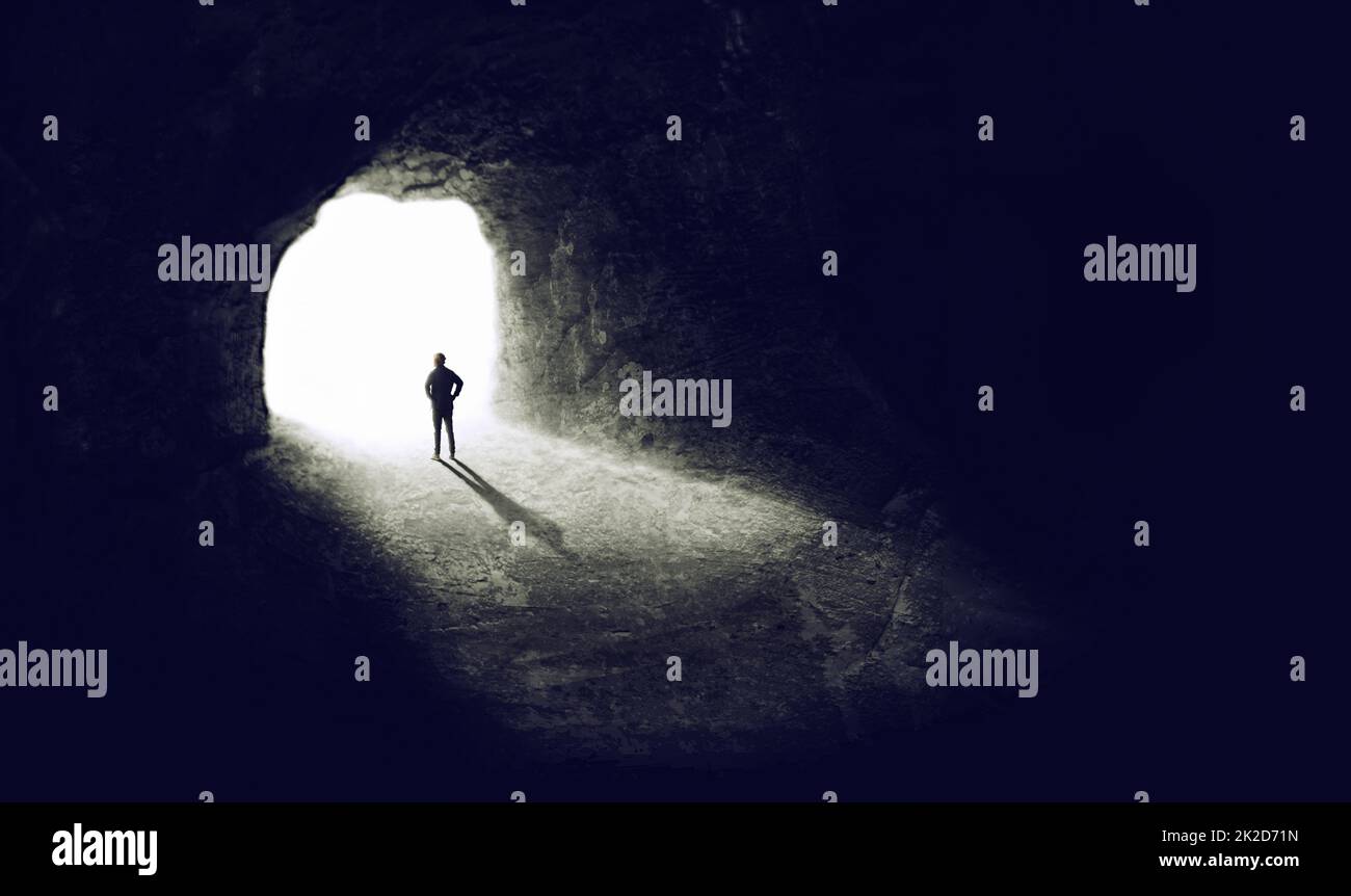 Trouver la lumière. Une photo d'une personne qui trouve une sortie d'un tunnel sombre. Banque D'Images