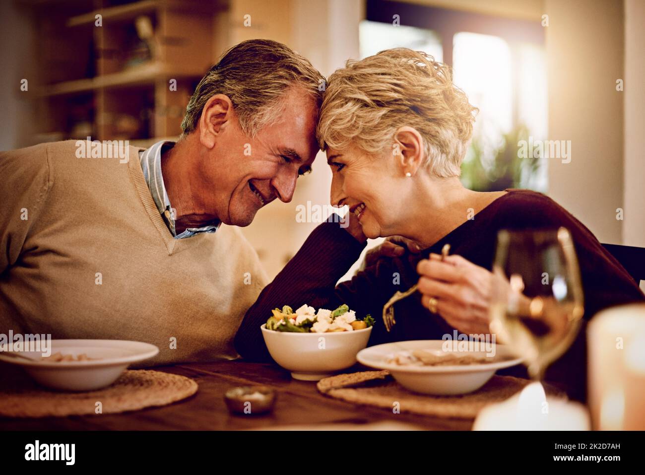 L'amour rend tout le goût meilleur. Prise de vue d'un couple de personnes âgées qui dégusté un repas et du vin à la maison. Banque D'Images