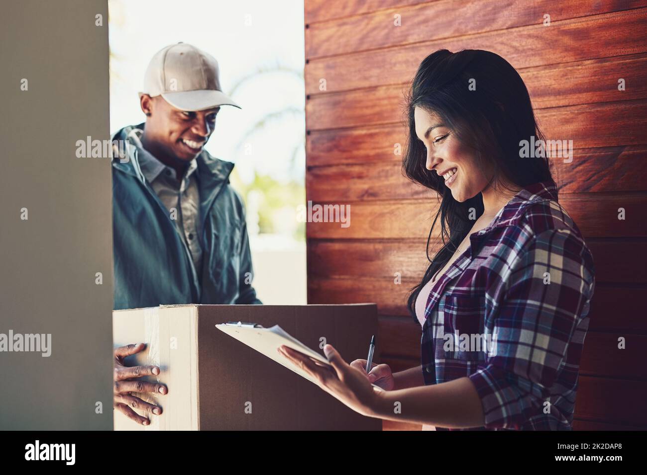 Je ne doute pas de faire usage de vos services rapides à nouveau. Photo d'une jeune femme qui signe pour son colis du messager. Banque D'Images