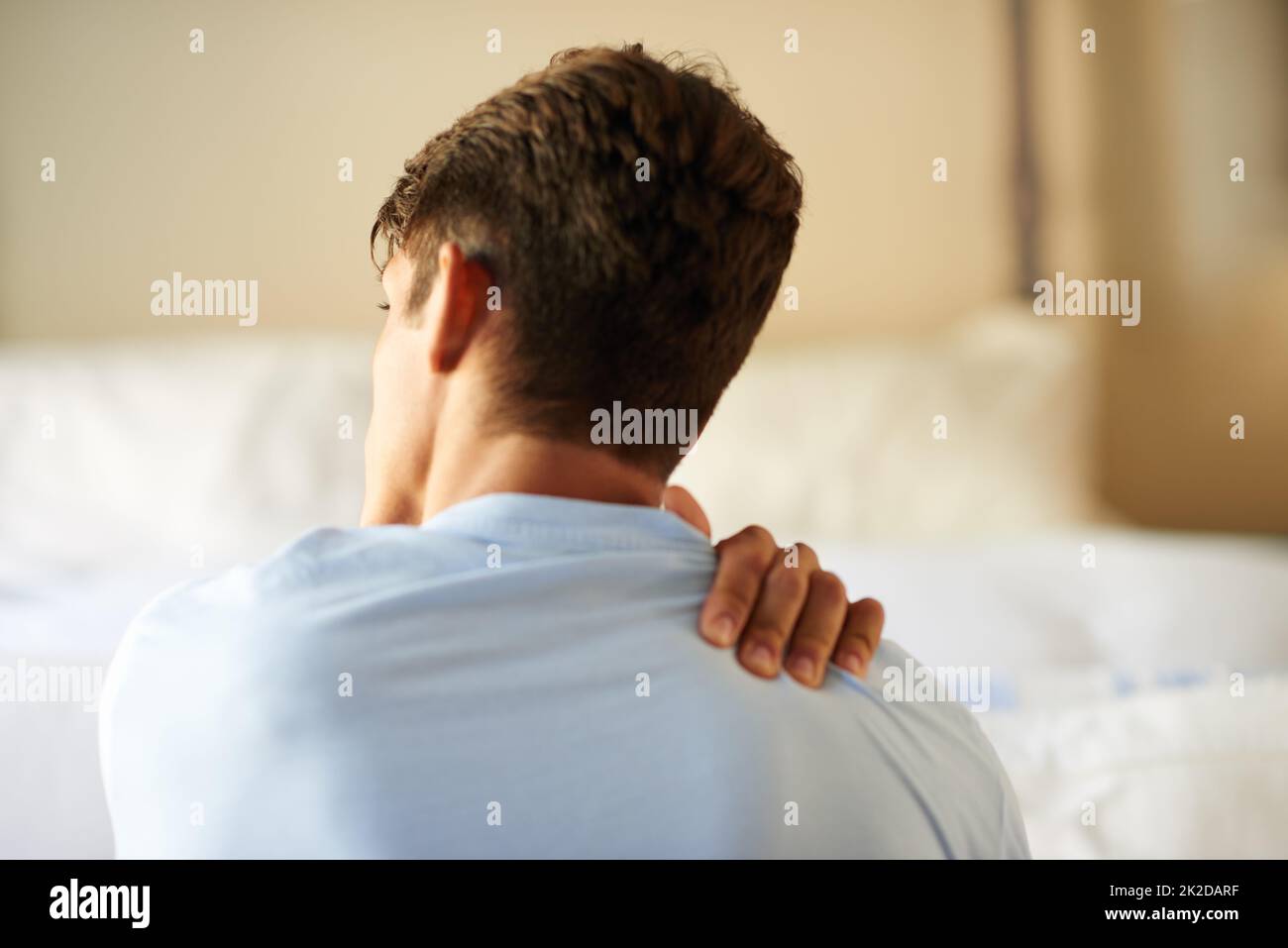 Cibler la douleur. Vue arrière d'un jeune homme souffrant d'une douleur au cou. Banque D'Images