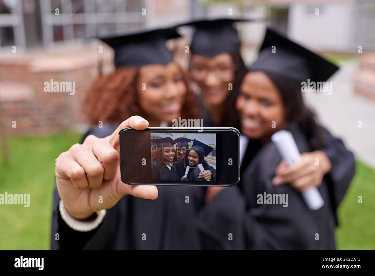 Souvenirs de moments monumentaux. Photo de trois femmes diplômées prenant une photo d'elles-mêmes au téléphone. Banque D'Images