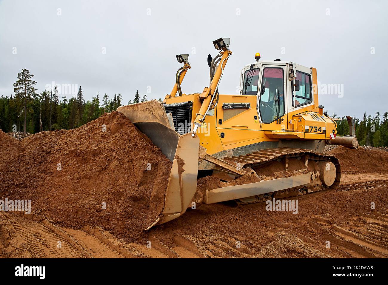 Un tracteur jaune nivelle le site avec du sable Banque D'Images