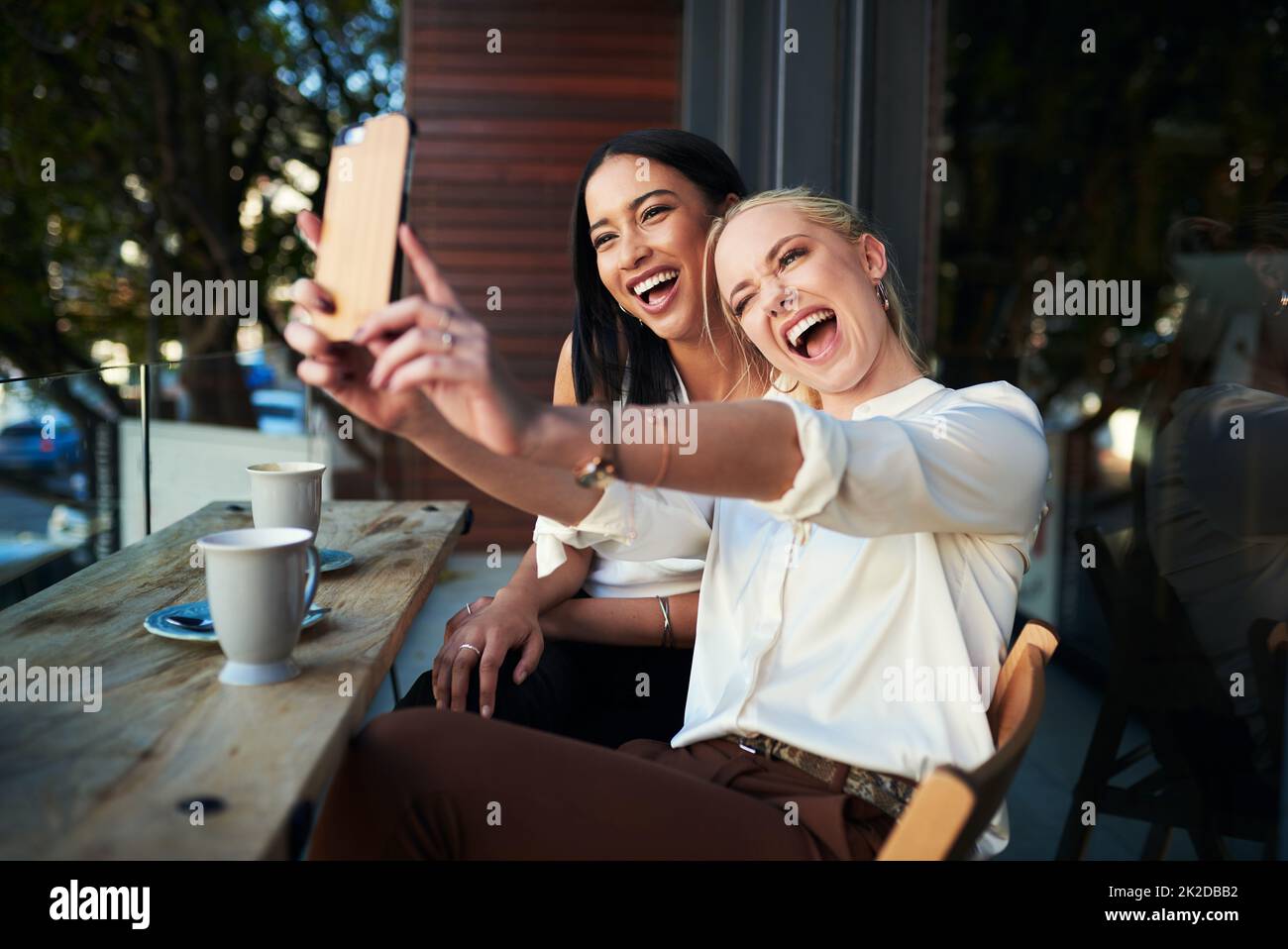 Les selfies du café-restaurant sont les meilleurs. Photo de deux jeunes femmes prenant un selfie tout en s'asseyant dans un café. Banque D'Images