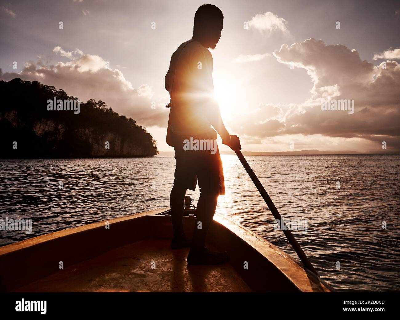 La voile vers une nouvelle aventure. Photo d'un jeune homme qui rame un bateau le long de la mer. Banque D'Images