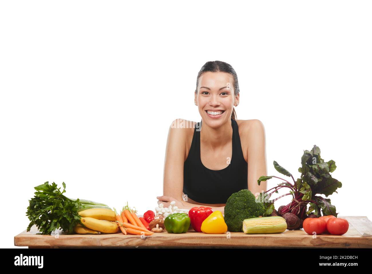 C'est aussi frais qu'il l'obtient. Studio portrait d'une jeune femme attrayante posant avec une table pleine de légumes sur un fond blanc. Banque D'Images