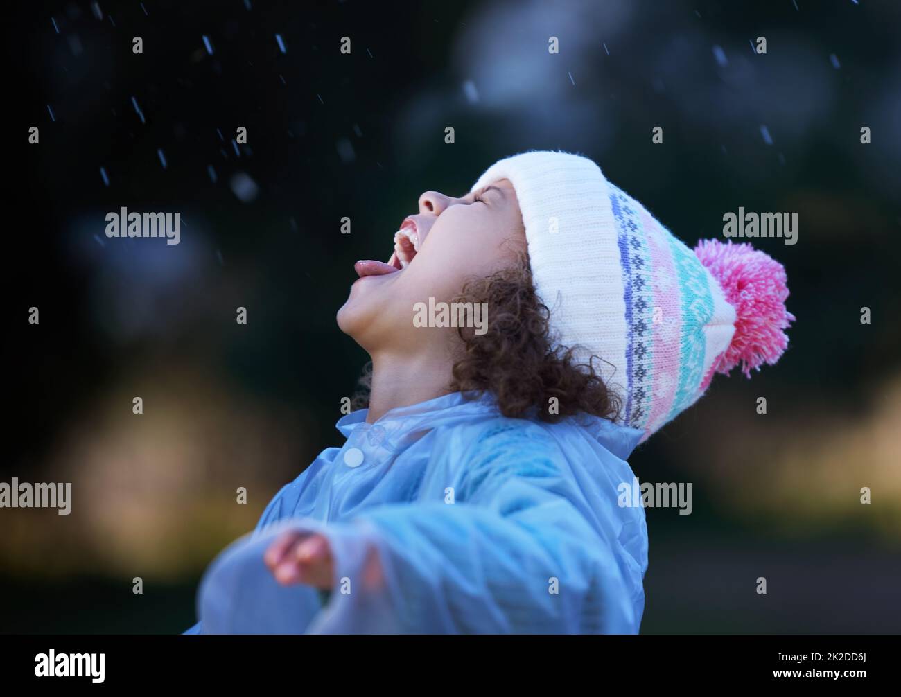 Tout le monde essaie de prendre des gouttes de pluie dans leur bouche. Photo d'une adorable petite fille debout seule à l'extérieur et jouant sous la pluie. Banque D'Images