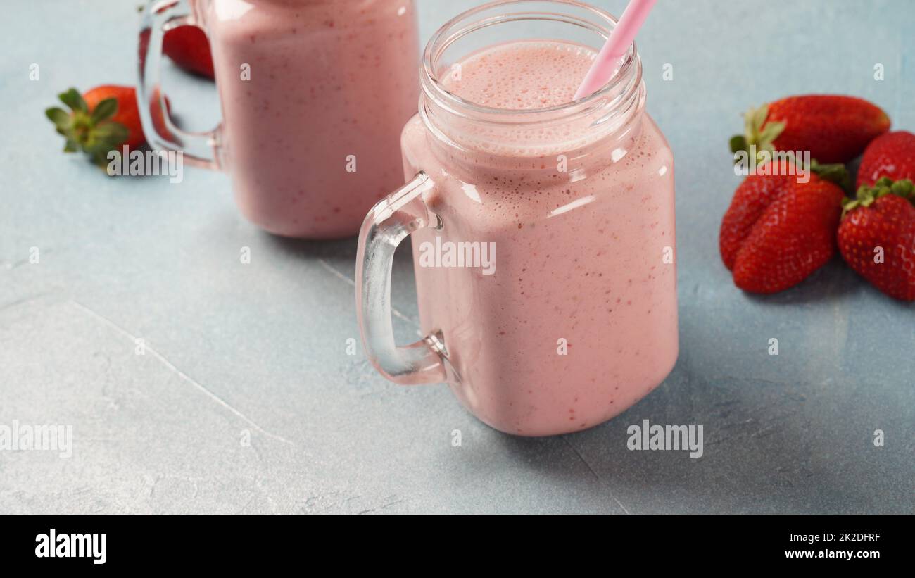 Milkshake aux fraises dans des pots de maçon avec des fraises fraîches Banque D'Images
