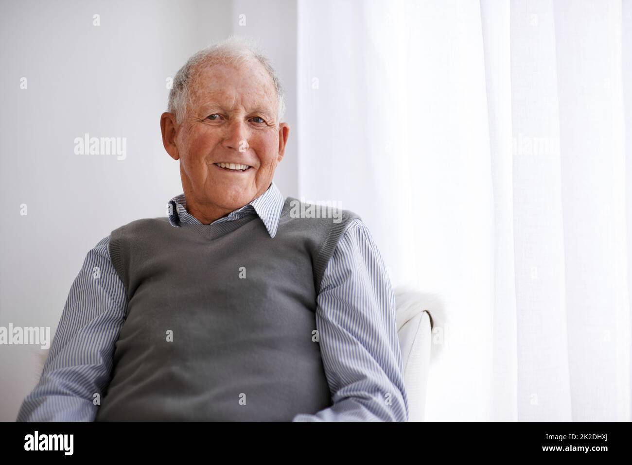 Les attitudes positives sont la voie à suivre. Portrait d'un homme âgé souriant se détendant dans une chaise. Banque D'Images