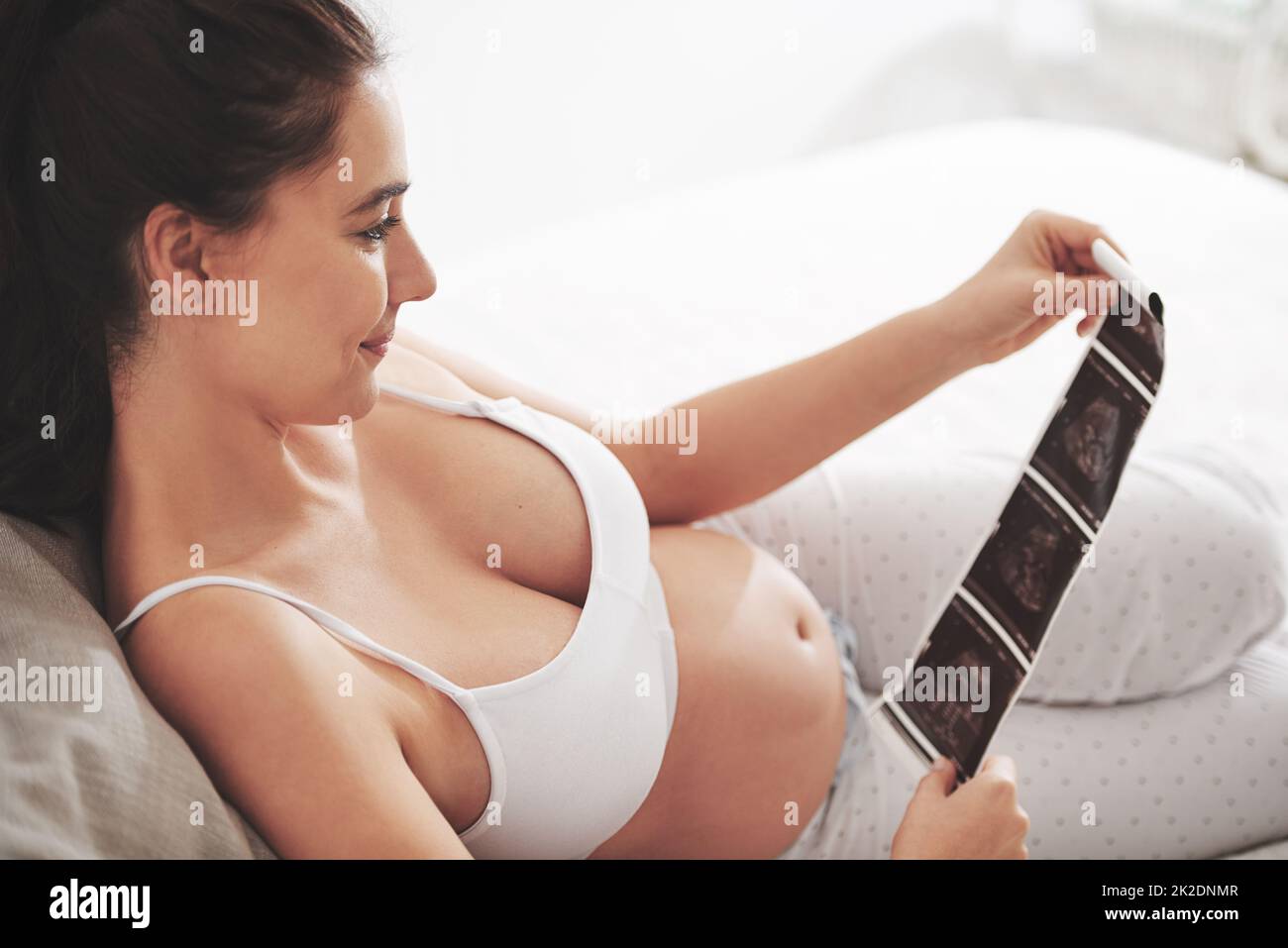 L'amour à première vue. Prise de vue d'une femme enceinte regardant une image d'un échogramme à la maison. Banque D'Images