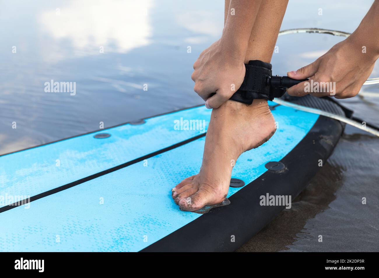 Une femme attache la laisse de surf sur sa cheville Banque D'Images