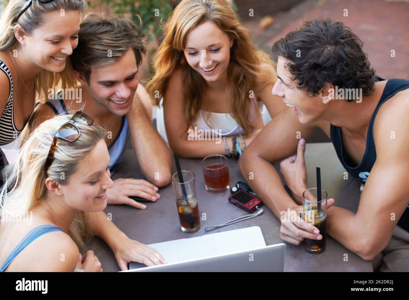 Regardez ceci. Groupe d'adolescents qui apprécient les boissons dans un restaurant en plein air avec toute leur technologie moderne. Banque D'Images