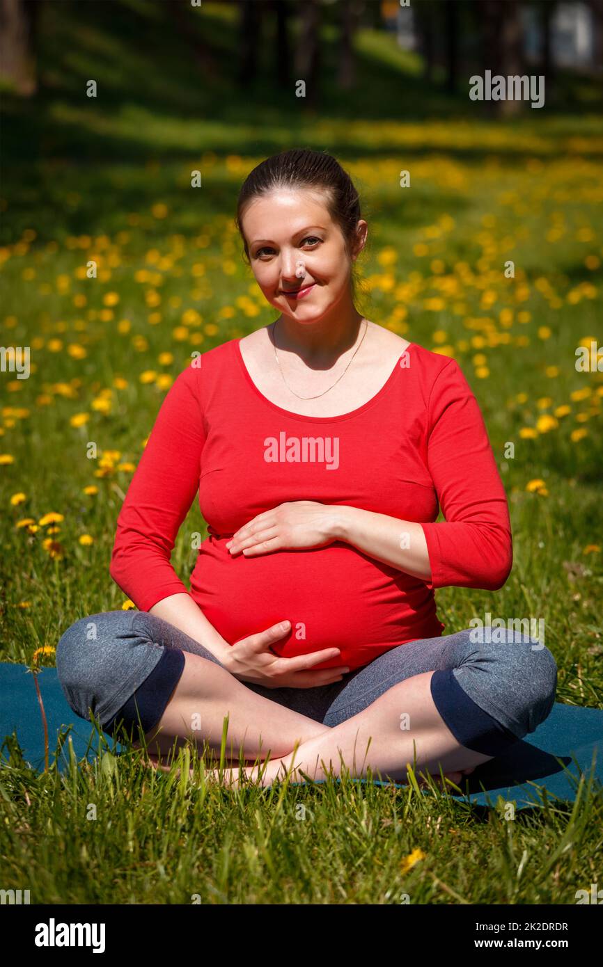 Femme enceinte faisant asana Sukhasana à l'extérieur Banque D'Images