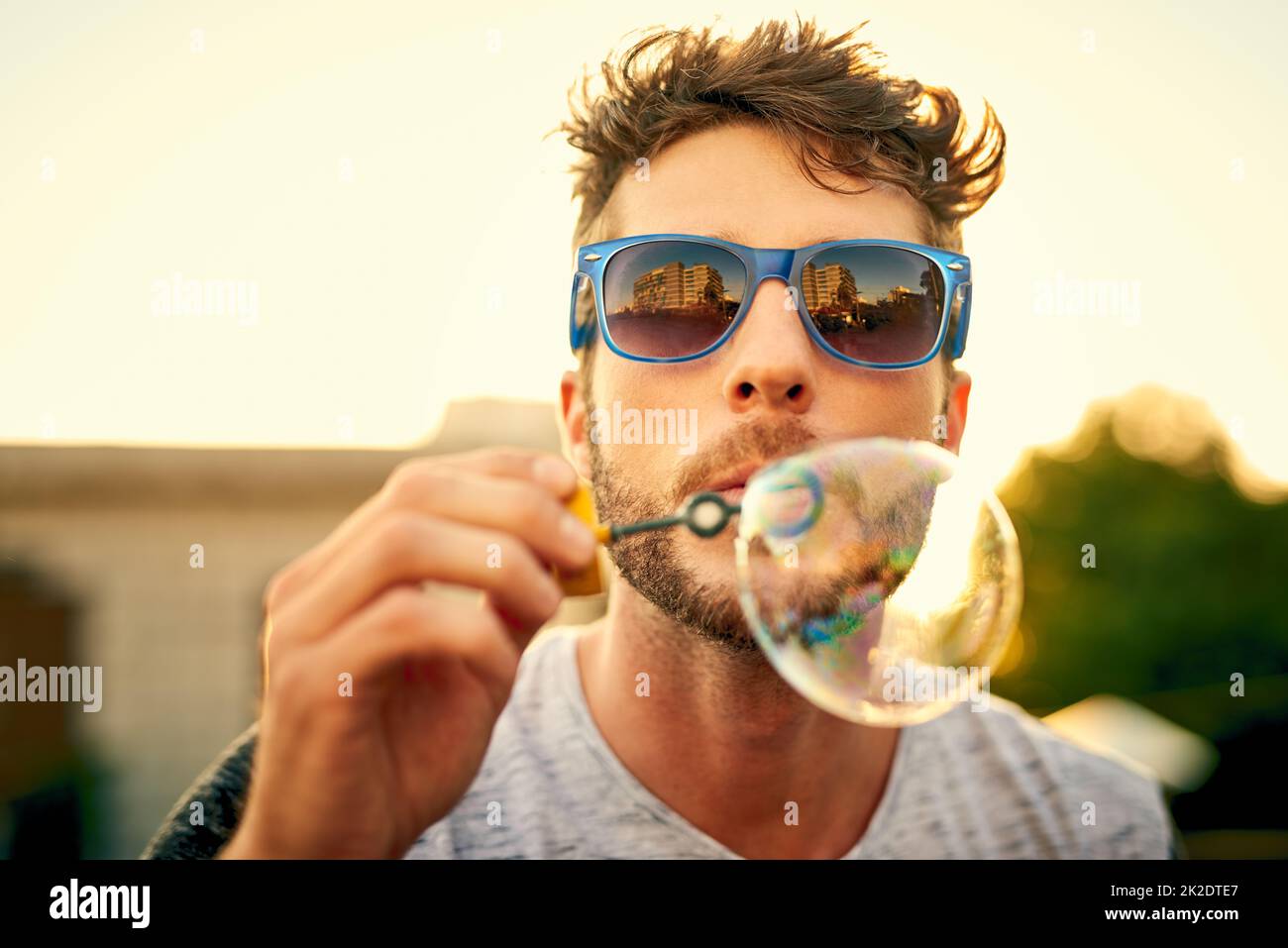 Notre enfant intérieur ne nous quitte jamais vraiment. Photo d'un jeune homme qui soufflait de bulles à l'extérieur. Banque D'Images