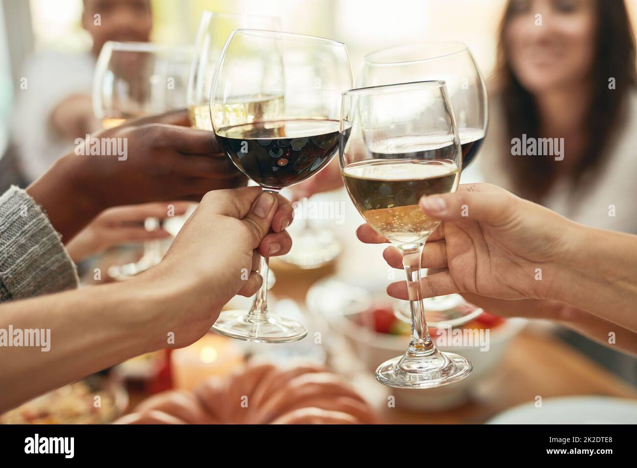 Vin un peu, rire beaucoup. Photo d'un groupe de personnes faisant un toast à une table de salle à manger. Banque D'Images