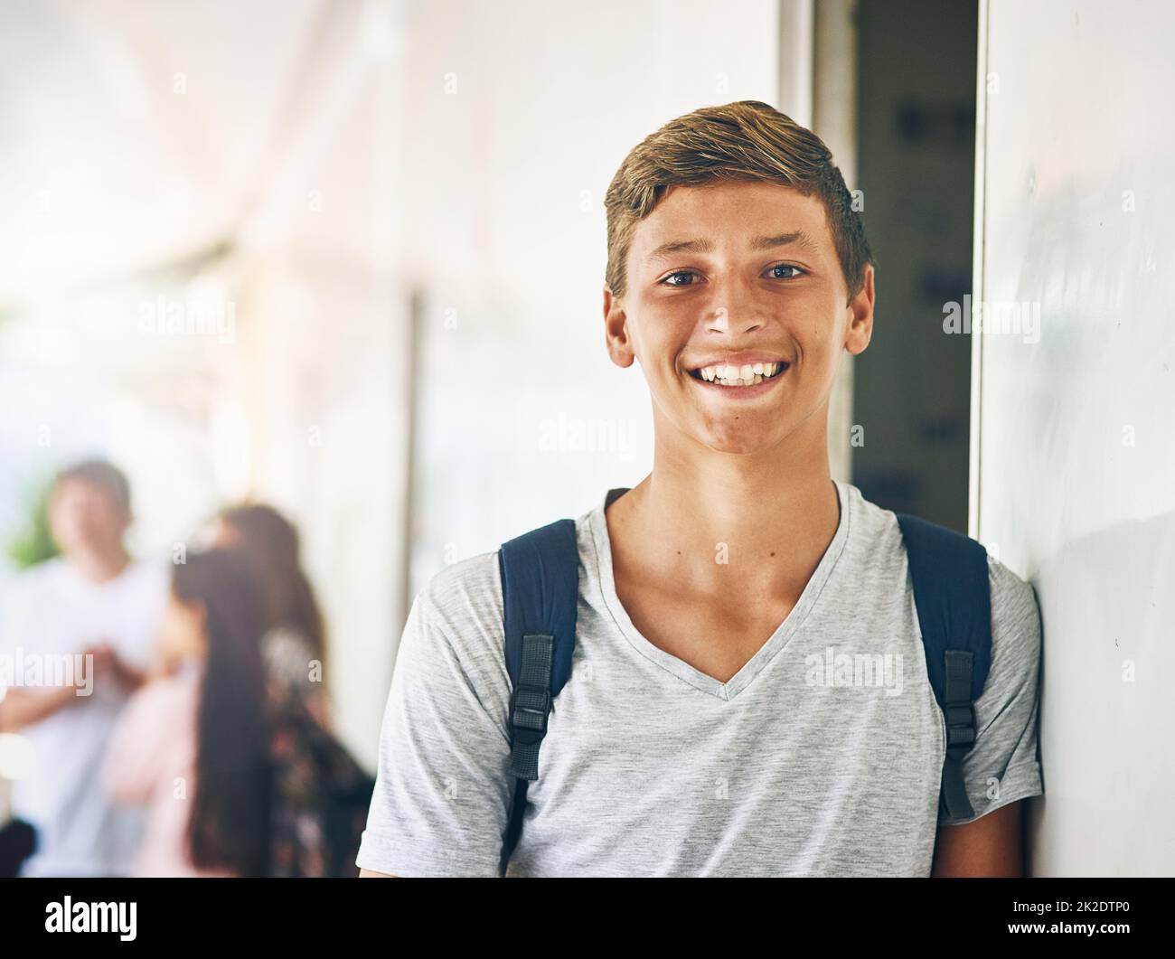 Mon avenir est brillant. Portrait d'un écolier heureux debout à l'extérieur de sa classe avec des camarades de classe en arrière-plan. Banque D'Images