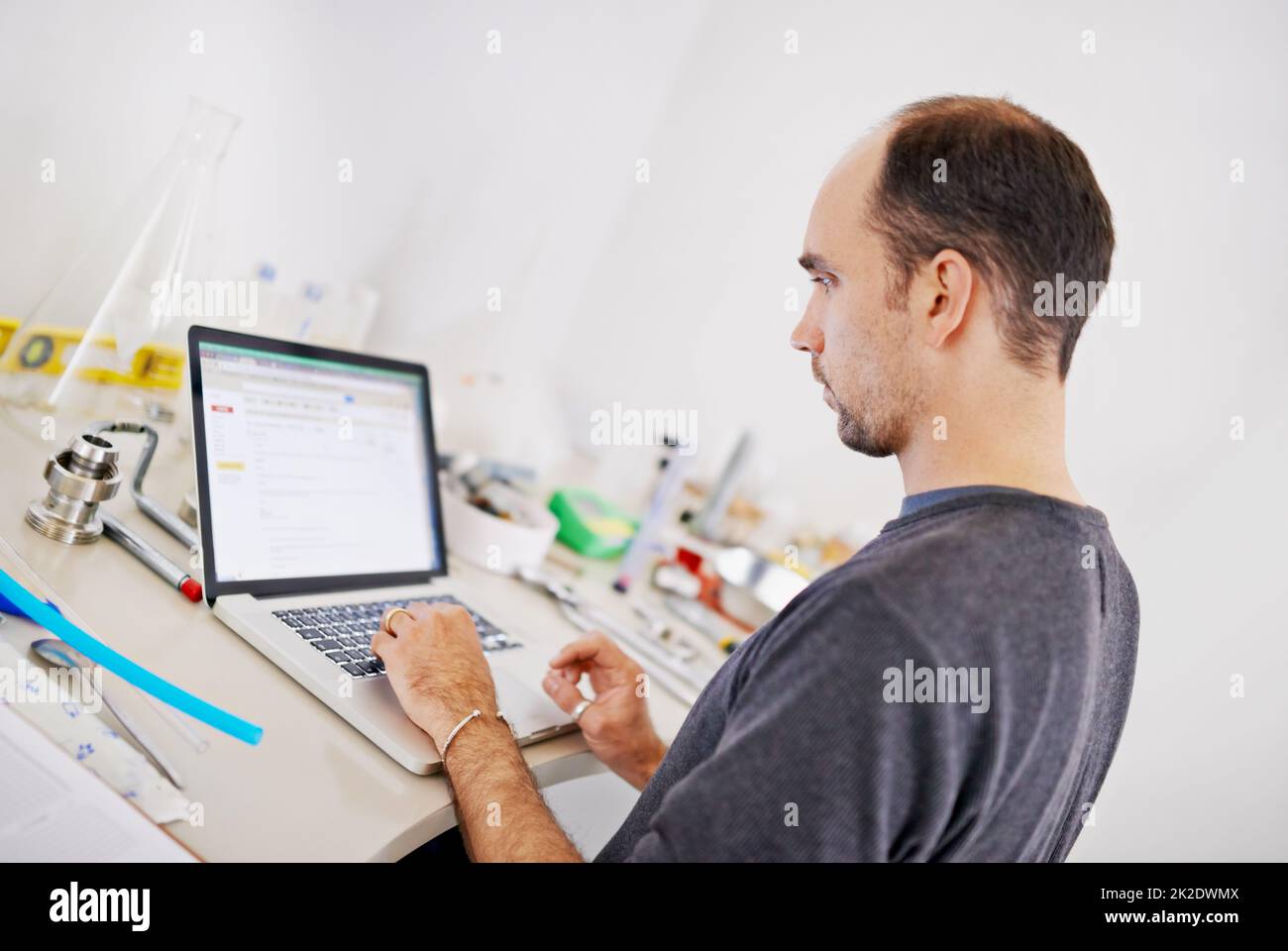 Perfectionnant son nouveau café. Photo d'un homme travaillant sur un ordinateur portable tout en étant entouré de matériel de brassage. Banque D'Images