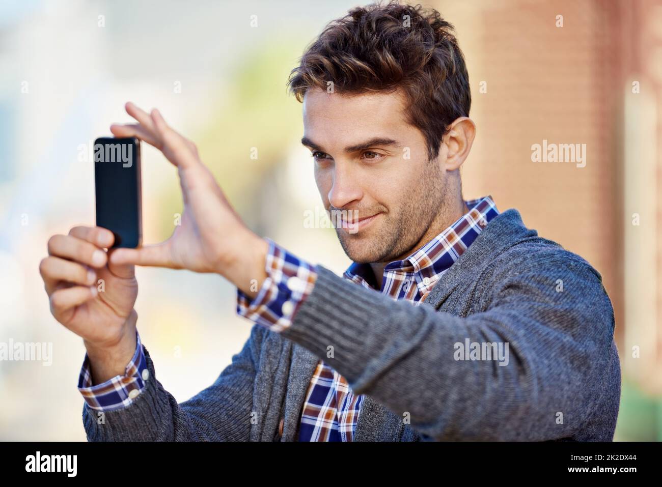 Photographie par téléphone. Photo d'un beau jeune homme prenant une photo avec son téléphone portable à l'extérieur. Banque D'Images