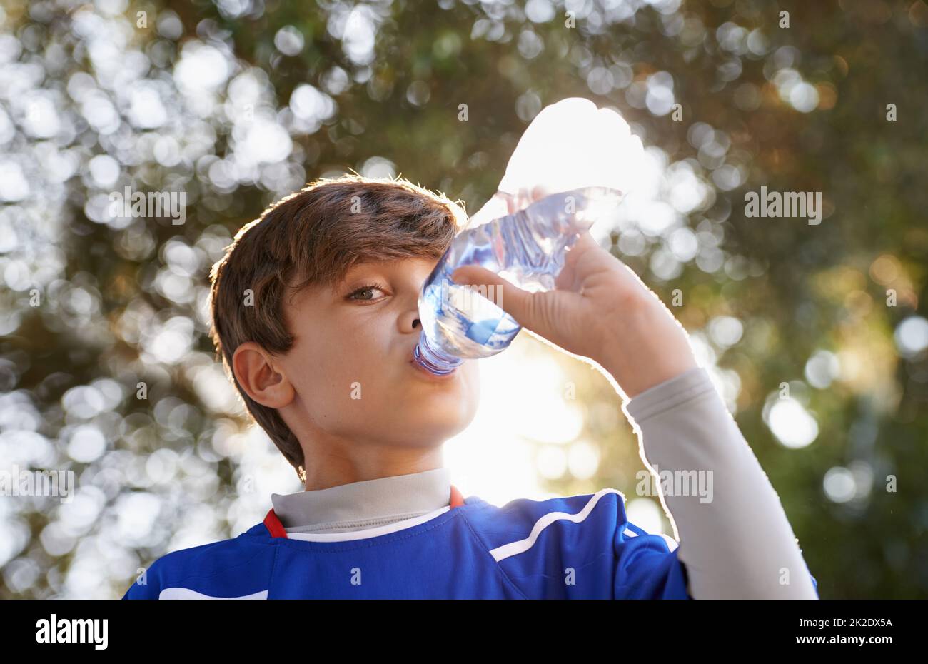 Les garçons seront des garçons. Photo d'un jeune garçon en vêtements de sport buvant une bouteille d'eau. Banque D'Images