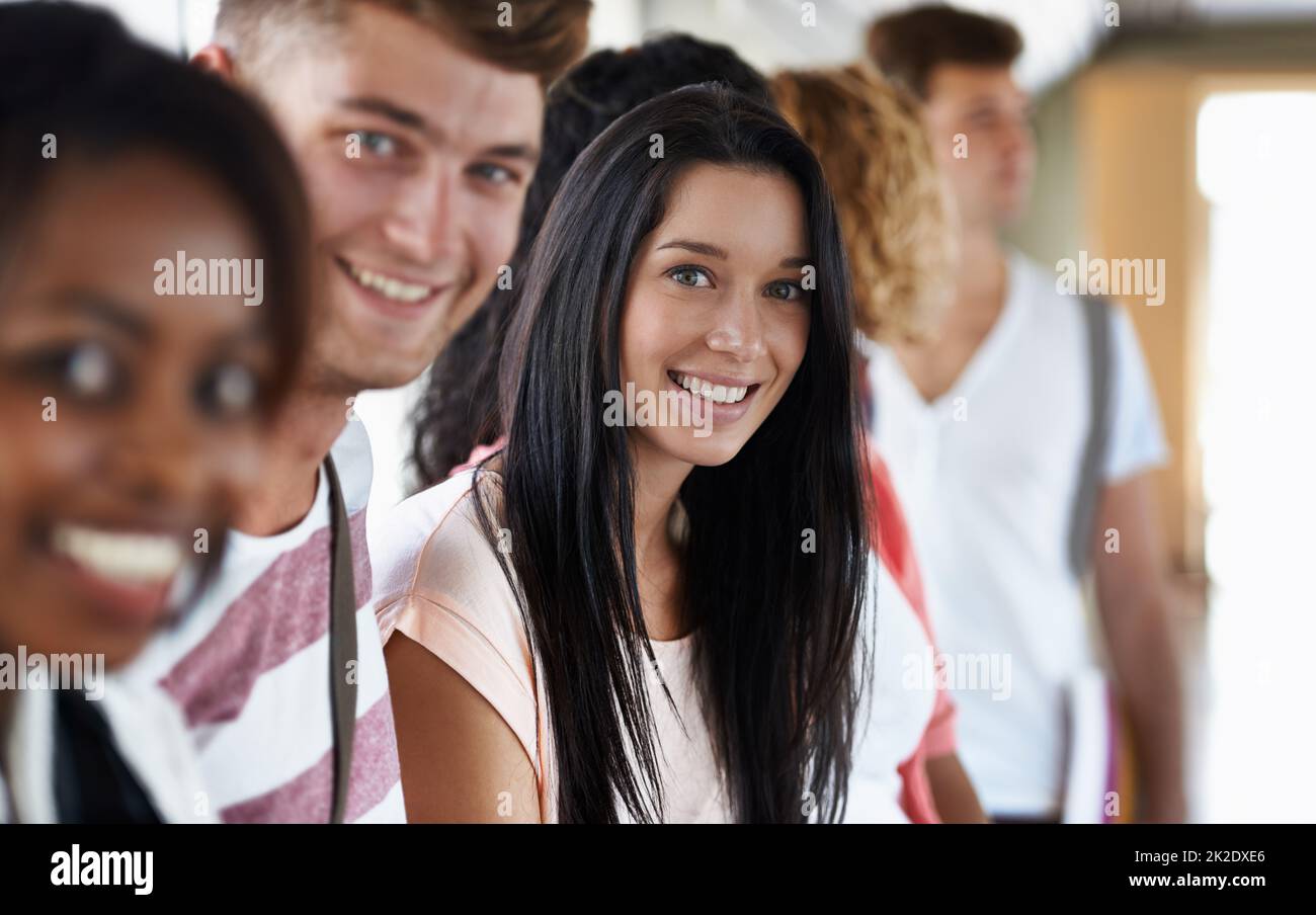Elle aime la vie universitaire. Portrait d'un beau jeune étudiant debout avec ses amis. Banque D'Images