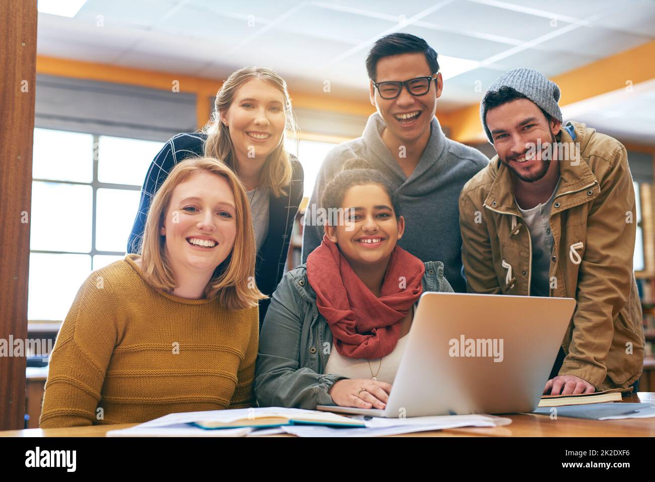 Il se sent un peu mieux lorsque vous étudiez ensemble. Portrait d'un jeune groupe joyeux d'étudiants travaillant ensemble à l'aide d'un ordinateur portable pour étudier pour des examens à l'intérieur d'une bibliothèque. Banque D'Images