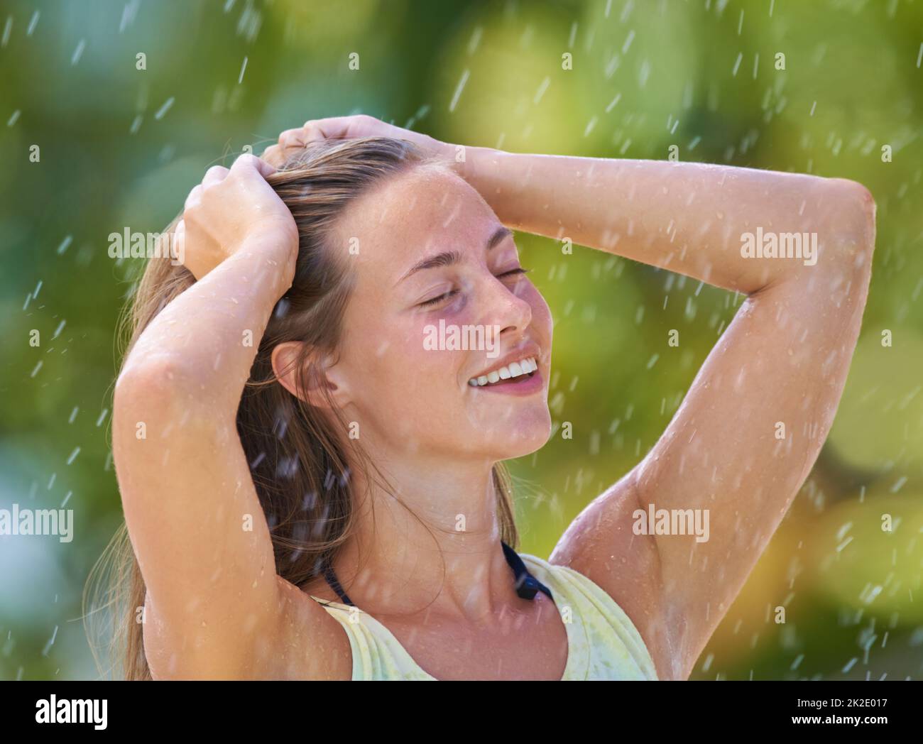 Pluie estivale sensationnelle. Photo courte d'une jeune femme debout avec joie sous la pluie. Banque D'Images