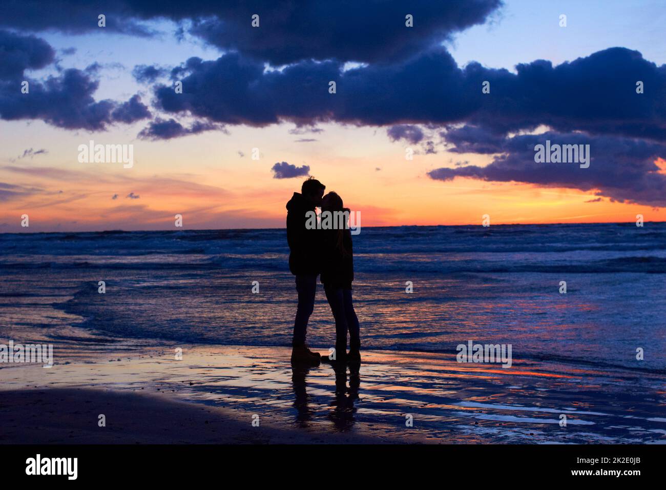 La nature est l'endroit idéal pour un séjour romantique. Silouehette d'un couple embrassant sur la plage au coucher du soleil. Banque D'Images