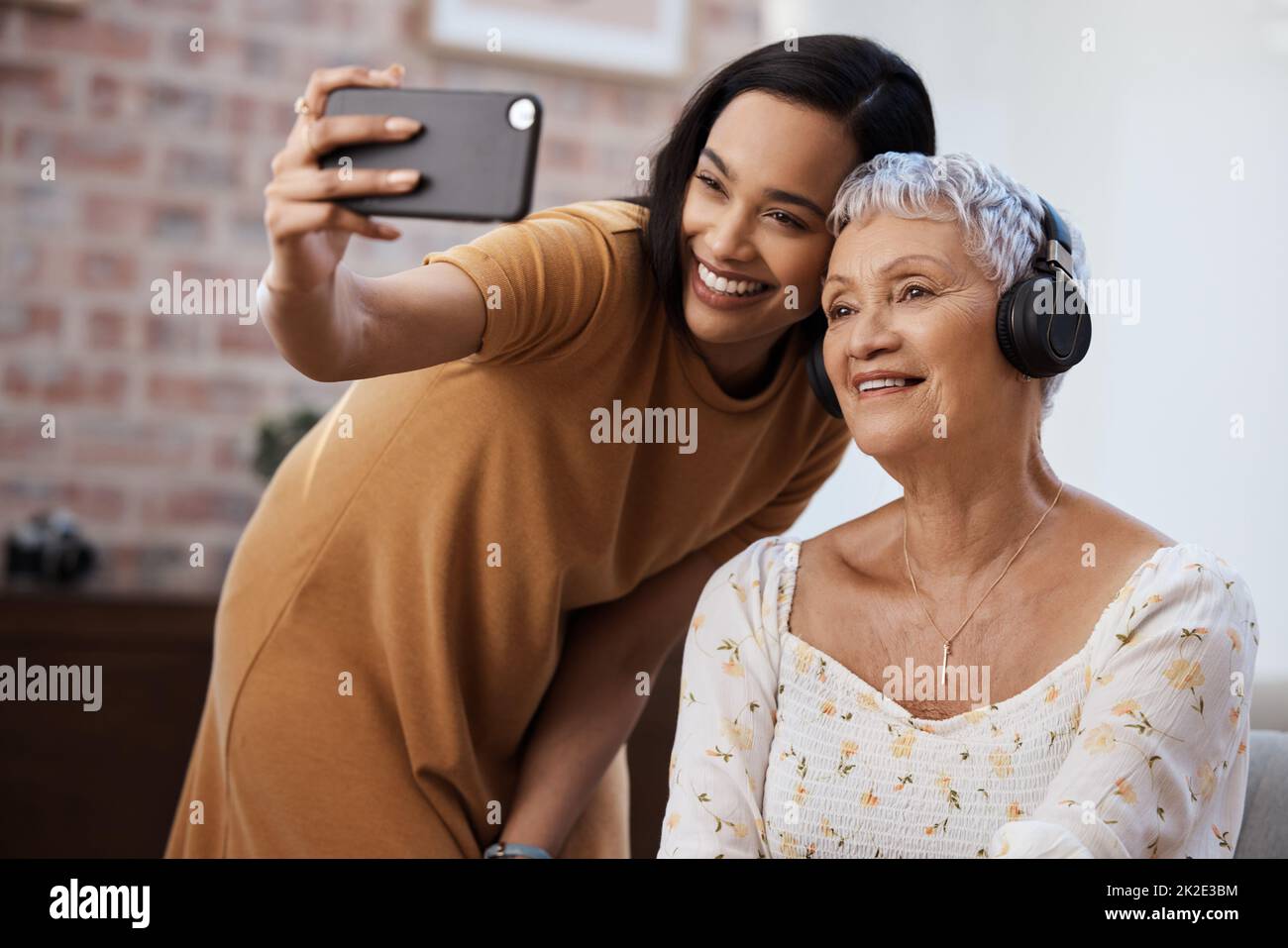 Nous disons que je vous aime avec un selfie. Photo d'une femme âgée utilisant un smartphone pour prendre des selfies avec sa fille à la maison. Banque D'Images