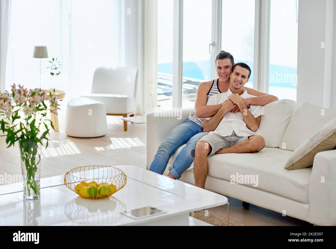Notre maison est pleine d'amour. Portrait d'un jeune couple gay se relaxant sur un canapé à la maison. Banque D'Images