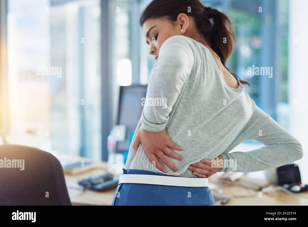 Quelle est cette forte piqûre dans mon dos. Photo d'une jeune femme d'affaires souffrant de douleurs dorsales pendant qu'elle travaille dans un bureau. Banque D'Images